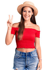 Young beautiful hispanic woman wearing summer hat smiling with happy face winking at the camera...