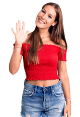 Young beautiful hispanic woman wearing casual clothes showing and pointing up with fingers number five while smiling confident and happy.