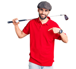Young handsome man with beard playing golf holding club and ball pointing finger to one self...