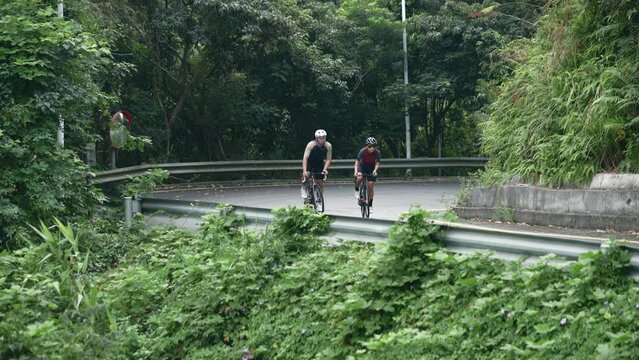 young asian couple cycling on rural road
