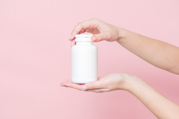 Blank white plastic tube in hand on pink background. Cosmetics beauty mockup for product branding