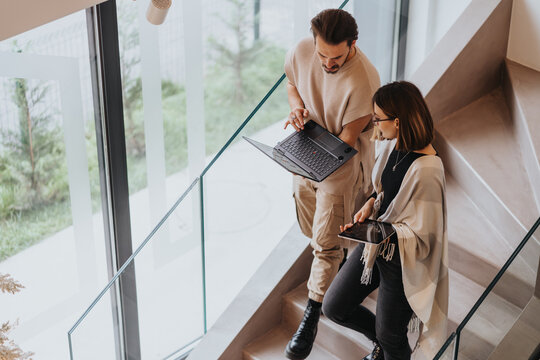 Confident coworkers collaborate in a modern office, discussing project solutions and analyzing statistics.