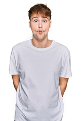 Obraz premium Young caucasian man wearing casual white t shirt making fish face with lips, crazy and comical gesture. funny expression.