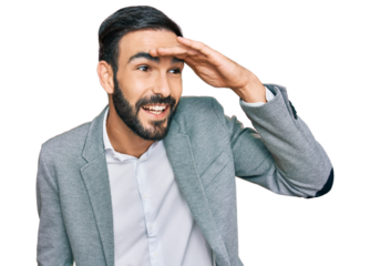 Young hispanic man wearing business clothes very happy and smiling looking far away with hand over head. searching concept.
