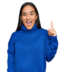 Young asian woman wearing casual winter sweater pointing finger up with successful idea. exited and...