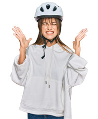 Teenager caucasian girl wearing bike helmet celebrating mad and crazy for success with arms raised and closed eyes screaming excited. winner concept