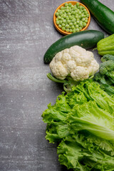 creative layout of healthy vegetables composed of lettuce, cucumbers, broccoli, green beans, peas, turnip, cabbage, chayote at gray background, copy space