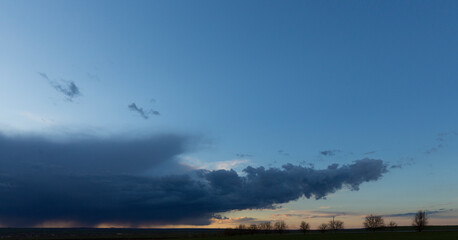 Obraz na płótnie Canvas Landscape at sunset. A thunderstorm is approaching the village. Tragic gloomy sky. Panorama.