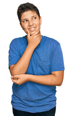 Teenager hispanic boy wearing casual clothes with hand on chin thinking about question, pensive...