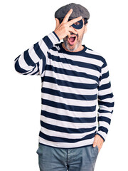 Fototapeta premium Middle age handsome man wearing burglar mask peeking in shock covering face and eyes with hand, looking through fingers with embarrassed expression.
