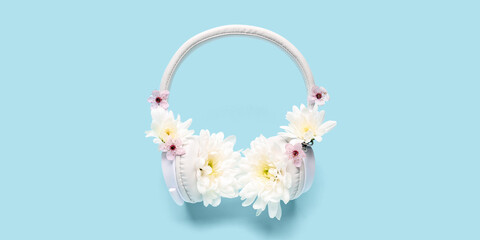 Modern headphones and chrysanthemum flowers on blue background