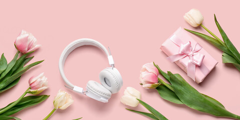Modern headphones, gift and beautiful tulip flowers on pink background