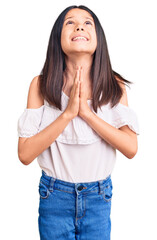 Beautiful child girl wearing casual clothes begging and praying with hands together with hope expression on face very emotional and worried. begging.