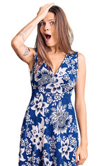Beautiful caucasian woman wearing summer dress surprised with hand on head for mistake, remember...