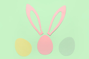 Fototapeta premium Paper bunny ears and Easter eggs on green background