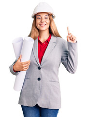 Beautiful young woman wearing architect hardhat holding build project surprised with an idea or question pointing finger with happy face, number one