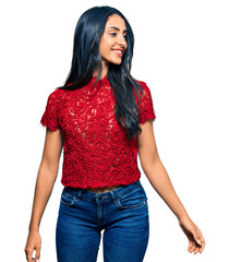 Fototapeta premium Beautiful hispanic woman wearing elegant shirt looking away to side with smile on face, natural expression. laughing confident.