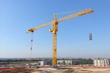 Fototapeta na wymiar Yellow construction crane working on a building site amidst construction activities