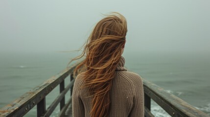 Back view of a woman with long hair, standing on a pier and looking out at a calm sea generative ai