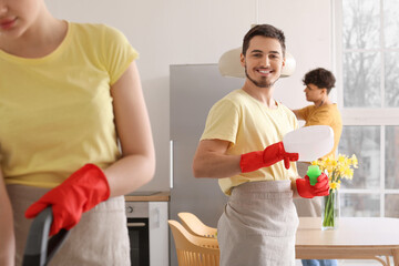 Male janitor with bottle of detergent in kitchen