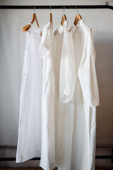 Fototapeta premium White women's clothing on hangers in a retail shop. Fashion and shopping concept.
