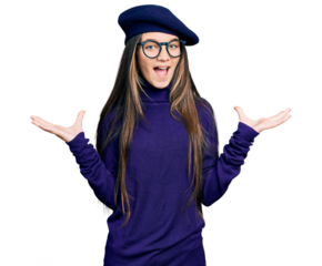 Young brunette girl with long hair wearing french look with beret and glasses celebrating victory with happy smile and winner expression with raised hands