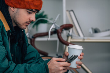 young man at home with mobile phone wearing warm or winter clothes