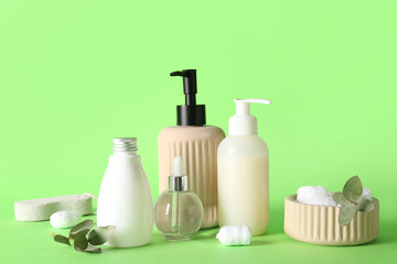 Bottles of cosmetic products and cotton balls on green background