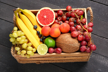 Box with different fresh fruits on black wooden background