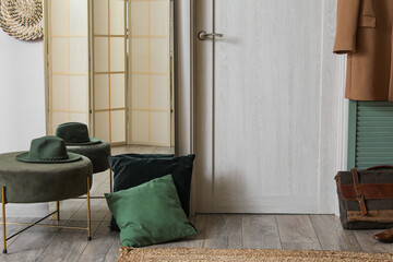 Interior of hallway with mirror, pouf and cushions