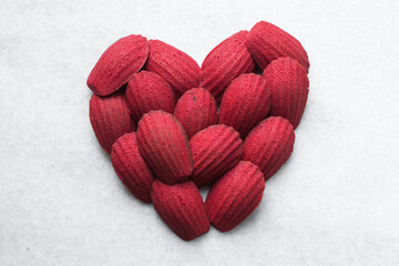 Fototapeta premium Red velvet madeleines on a marble tray shaped like a heart, red madeleines cake or cookies for valentines