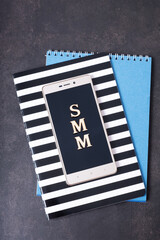 Abbreviation SMM made with wooden letters on phone, top view. Social Media Marketing