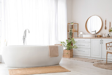 Interior of light bathroom with sink, accessories and bathtub