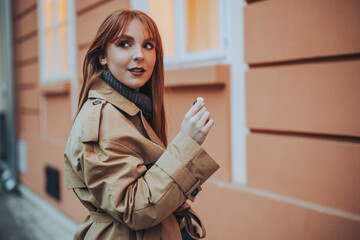 A young trendy woman is holding earphones in her hand and smiling.