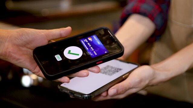 Closeup customer hand hold mobilephone making cashless payment in retails small business cafe coffee restaurant shop, cashier using qr code billing credit card, contactless online wireless application