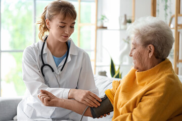 Doctor measuring blood pressure of senior woman at home