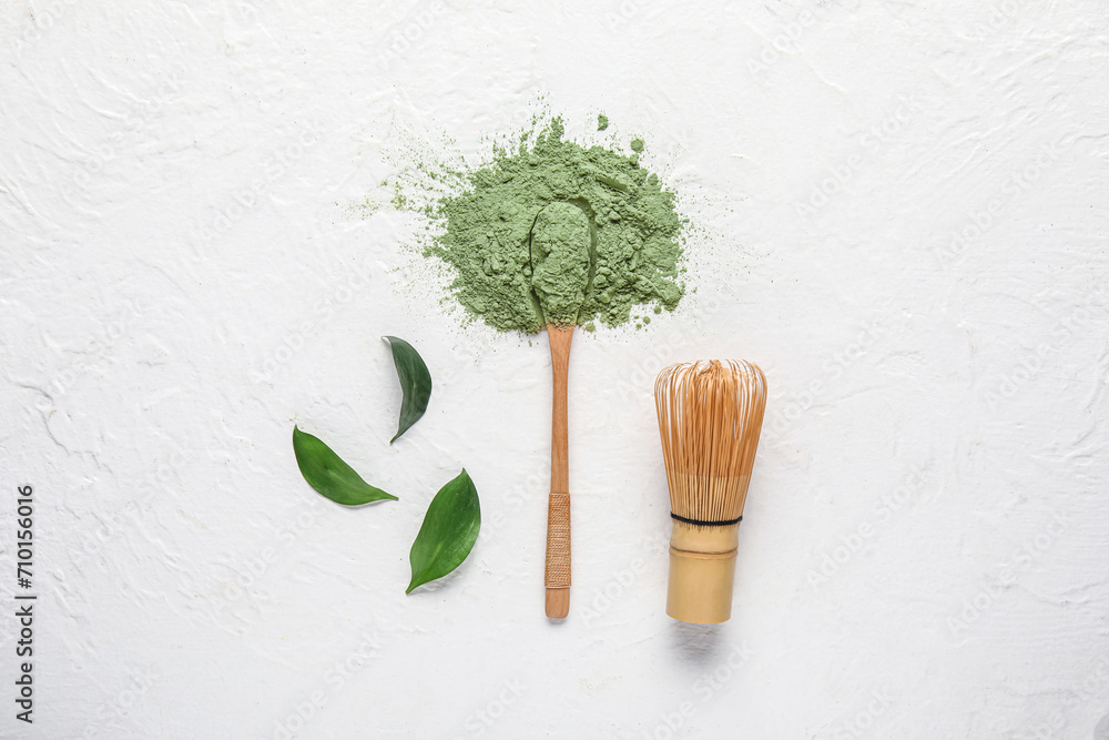 Wall mural Heap of powdered matcha tea, spoon and chasen on light background