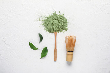 Heap of powdered matcha tea, spoon and chasen on light background