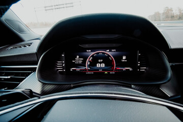 Digital screen dashboard in a sports car cockpit with odometer close up still