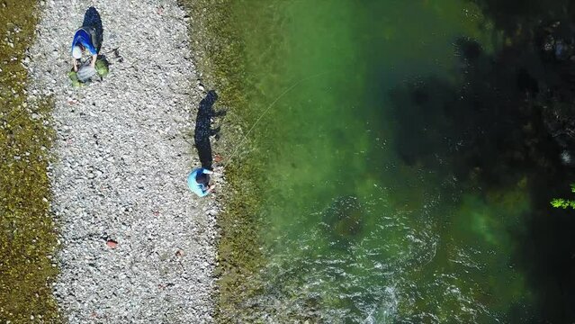 Drone footage of fisherman fly fishing in river in the mountains in summer. Mozirje, Slovenia