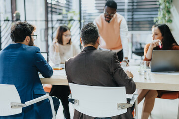 A diverse group collaborates in a modern office setting, discussing business strategies, market research, and financial statistics. The team works together towards sustainable growth and profit.