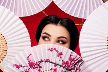 Photo of graceful elegant asian lady close face japanese folding fan looking up empty space on red color background