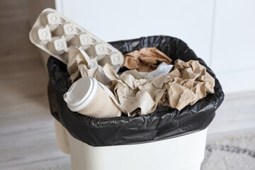 Full trash bin with different garbage in kitchen, closeup
