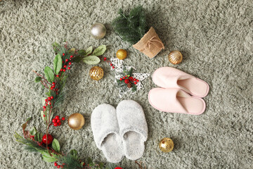 Fototapeta na wymiar Soft slippers with Christmas decor on green carpet, top view