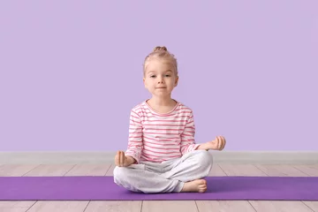 Fotobehang Lotusbloem Cute little girl sitting in lotus pose on yoga mat against lilac background  © Pixel-Shot