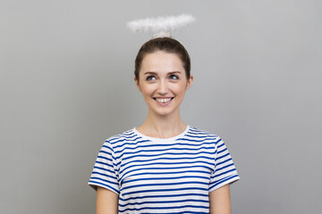 Portrait of smiling woman wearing striped T-shirt and with nimbus over her head looking up with...