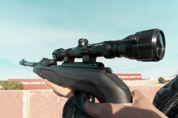 A rifle with an optical sight close-up in the hands of a man, selective focus. Military action,...