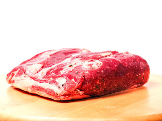 Uncooked strip loin joint on old wooden board and on white background. Raw high quality and price piece of beef meat.