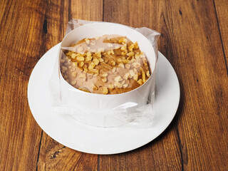 Small cake with nuts in plastic wrap on wooden board. Premium high quality dessert products. Tasty snack