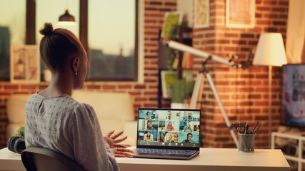 African american girl on videocall doing briefing meeting for new research plan to solve online tasks. Woman waving at videoconference webcam, using laptop at home. Tripod shot.